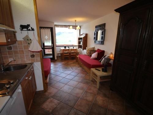 Il comprend une cuisine et un salon avec un canapé rouge. dans l'établissement Les Saisies - Studio cabine rénové 4/5 pers avec terrasse exposée sud, animaux tolérés. - FR-1-293-161, aux Saisies