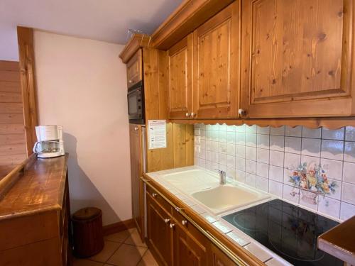 une cuisine avec des armoires en bois et un évier dans l'établissement Appartement cosy avec 2 bains, piscine, proche pistes et commerces - Hauteluce - FR-1-293-356, à Hauteluce