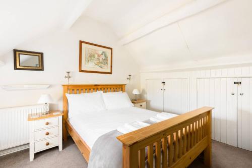 a bedroom with a bed with a wooden headboard at Pass the Keys Cosy Cottage 17th century Garden Parking in Bourton on the Hill