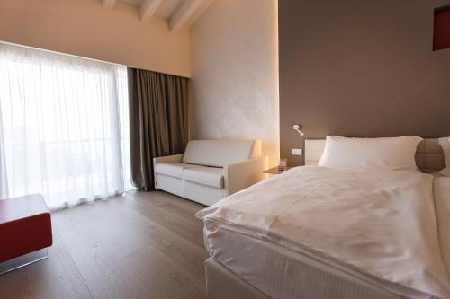 a hotel room with a bed and a chair and a window at Locanda Monte Baldo in Malcesine