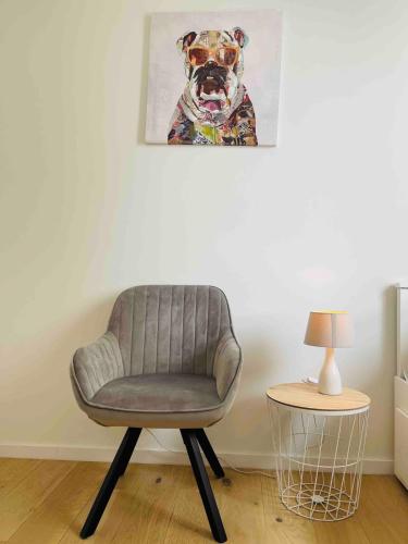 a chair in a room with a picture of a dog at Basel-Tram 8-Tristate-Bridge-Riverview in Huningue