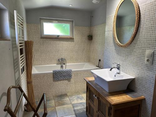 une salle de bain avec un lavabo, une baignoire et un miroir dans l'établissement chez Marie, petit cocon avec piscine, à Saint-Avit-Saint-Nazaire