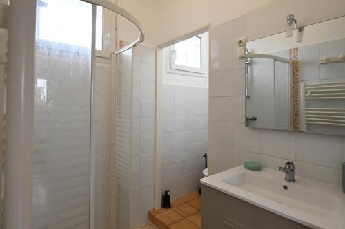 a white bathroom with a sink and a shower at La Pause Royannaise - 500 m de la plage in Royan