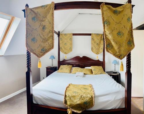 - une chambre avec un lit à baldaquin et des oreillers jaunes dans l'établissement Relais Guinguette, à Tinténiac