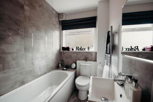 a bathroom with a tub and a toilet and a sink at Hinckley Flats in Hinckley