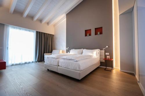 a bedroom with a white bed and a large window at Locanda Monte Baldo in Malcesine