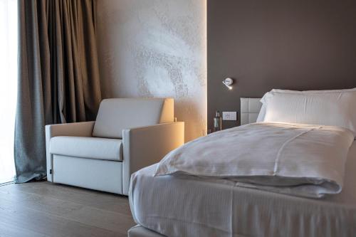 a bedroom with a white bed and a chair at Locanda Monte Baldo in Malcesine