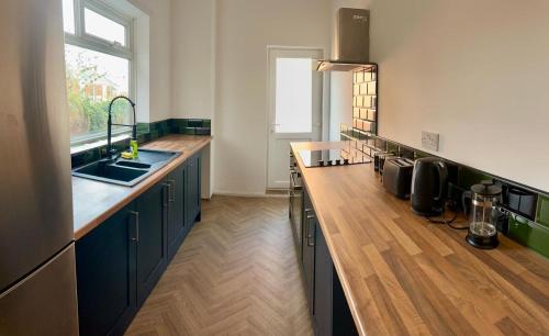 a kitchen with black cabinets and a wooden floor at House In South Tyneside in Hebburn-on-Tyne