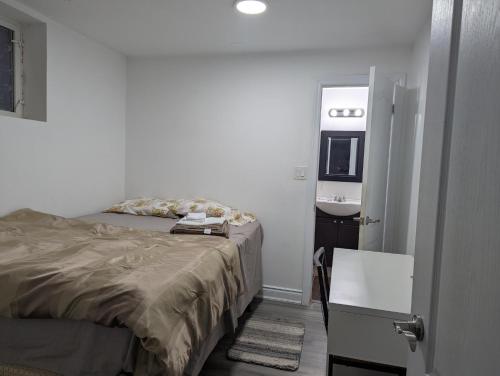 a small bedroom with a bed and a sink at Basement two Queen beds and one single with two full washrooms by YKF airport in Kitchener