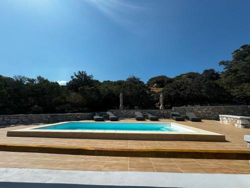 a swimming pool in a patio with chairs at Caldera Suites "Φάρος" in Galissas