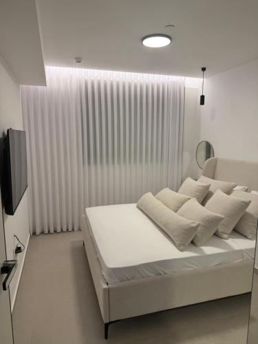 a bedroom with a large white bed with white pillows at ירדן דירת גן אדריכלית סוויטה פרטית in Eilat