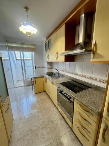 a kitchen with wooden cabinets and a stove top oven at As Marismas - Miño in Miño