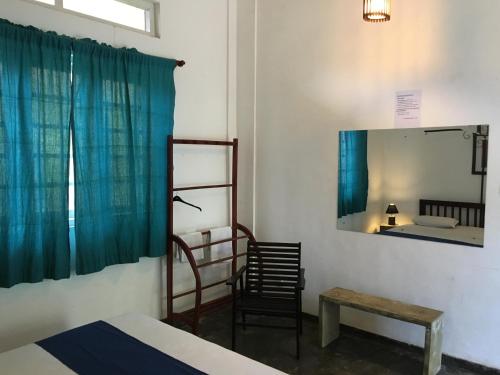a room with a bed and a mirror and a chair at Colombo Beach Hostel in Mount Lavinia
