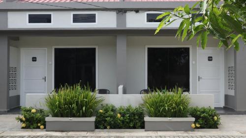 a white house with three doors and some plants at Cataleya Homestay Lagoi Bintan in Sebungsungai