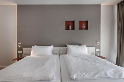 two beds in a bedroom with white sheets and pillows at Locanda Monte Baldo in Malcesine