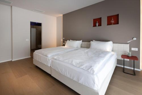 a large white bed in a bedroom with a red table at Locanda Monte Baldo in Malcesine