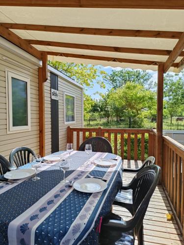 una mesa y sillas en una terraza de madera en Mobil home - 4 Etoiles - 3 chambres, en Vias