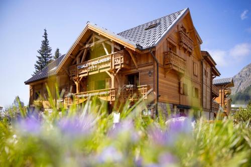 a large wooden house with a balcony and flowers at Hôtel Chalet Mounier in Les Deux Alpes