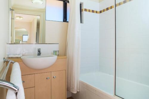 a bathroom with a white sink and a shower at City Plaza Apartments in Cairns
