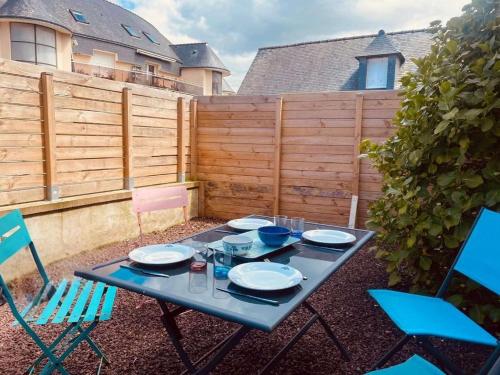 トレガステルにあるBeau T2 Trégastel avec jardin, proche plages et commercesのパティオ(テーブル、椅子、皿付)