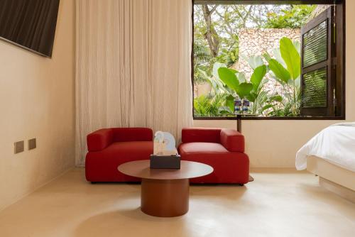 a bedroom with two red chairs and a table and a bed at Arde La Selva in Santa Fe de Antioquia