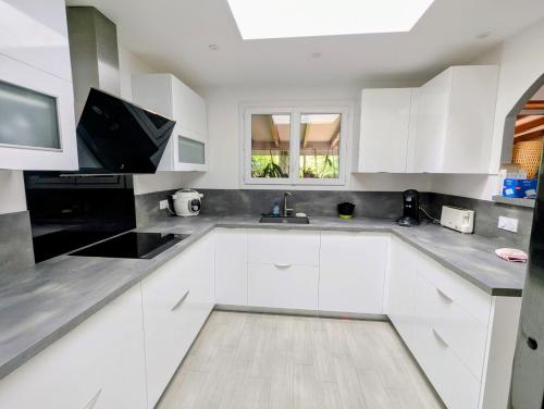 een witte keuken met witte kasten en een spoelbak bij Maison 3 étoiles climatisée, jardin, parking, proche centre et thermes in Dax