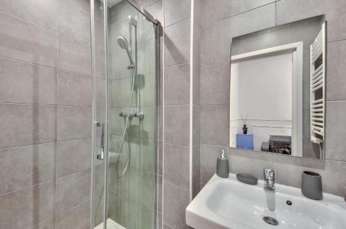 une salle de bain avec une douche, un lavabo et un miroir dans l'établissement Urban Flat 35 - 2 Bedroom Apartment Grands Boulevards, à Paris
