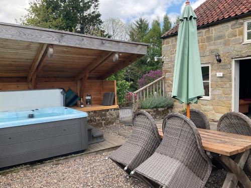 a patio with a hot tub and an umbrella at Beck cottage in Rosedale Abbey