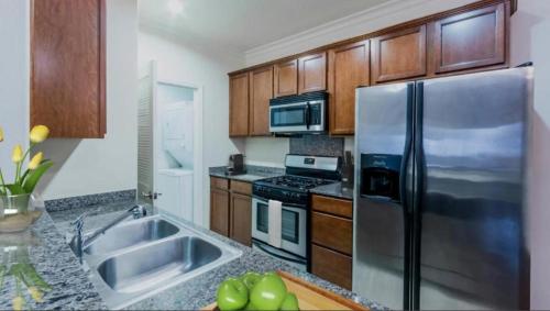 a kitchen with wooden cabinets and a stainless steel refrigerator at LALAs House- 1br with Free Parking, Pool and Sauna in Los Angeles