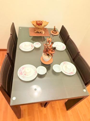 a green table with plates and a bowl on it at Park View Service Apartment By Kualalampur in Kuala Lumpur