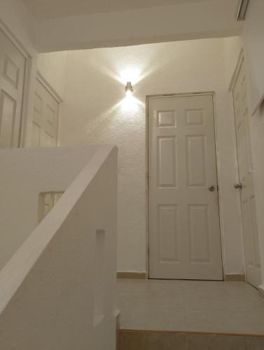 a white door in a white room with a staircase at Playa, amplitud y tranquilidad in Acapulco
