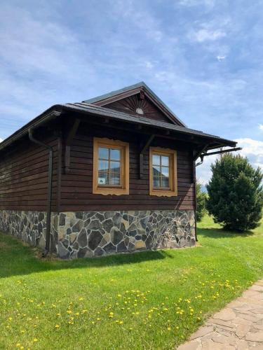 a log cabin with two windows on a green lawn at Chata 107 Tatralandia Village in Liptovský Mikuláš