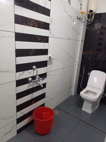 a bathroom with a toilet and a red trash can at VR Homes in Ernakulam