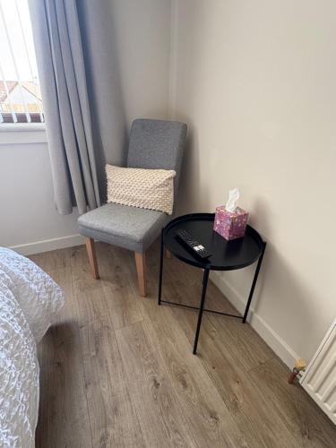 a small room with a chair and a table with a box on it at Carnegie Lodgings, Tain in Tain