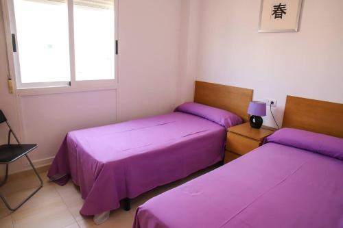 two beds in a room with purple sheets at Atico Piles in Piles