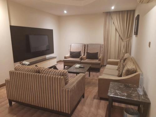 a living room with two couches and a flat screen tv at أسوار للشقق المخدومة in Al Khobar