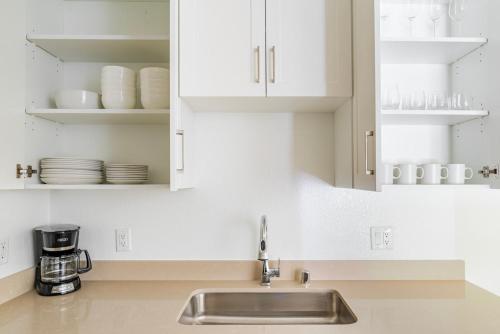 Una cocina con fregadero y gabinetes blancos. en Blueground Shoreline West pool nr Shoreline Park SFO-1858, en San Francisco