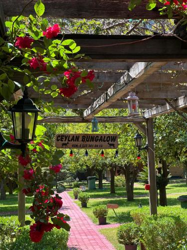 a sign for a garden with flowers and a pathway at Ceylan Bungalow in Cıralı