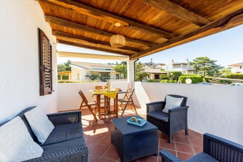 a patio with chairs and a table on a wall at Superb Loft Baja Sardinia -Panoramic Sea View- in Baja Sardinia