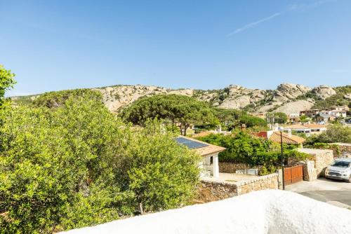 a house with a mountain in the background at Superb Loft Baja Sardinia -Panoramic Sea View- in Baja Sardinia