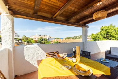 a dining table with a yellow table cloth on a balcony at Superb Loft Baja Sardinia -Panoramic Sea View- in Baja Sardinia