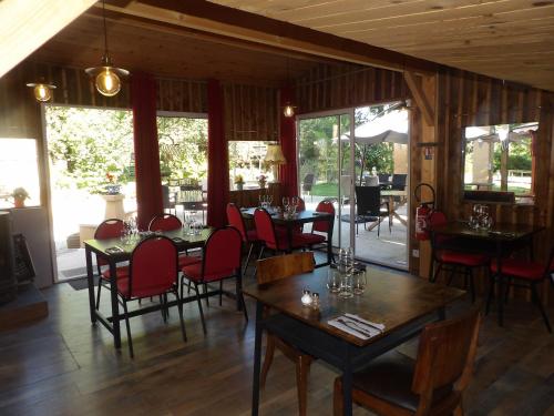 une salle à manger avec tables, chaises et fenêtres dans l'établissement L'auberge du moulin a grains, à Ménil-la-Horgne