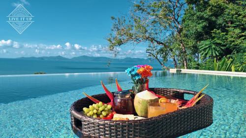 Ein Korb mit Obst und Gemüse steht neben einem Pool. in der Unterkunft Santi Pura Villas in Ban Bang Po