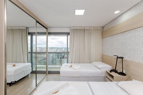 a hotel room with two beds and a large window at 7th Avenue - Centro | Curitiba | Gonzaga Stays in Curitiba