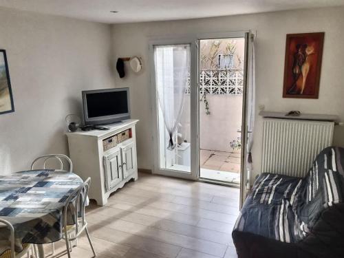 un salon avec une télévision et un canapé dans l'établissement Confortable pavillon avec jardin à 900m de la plage, à Valras-Plage
