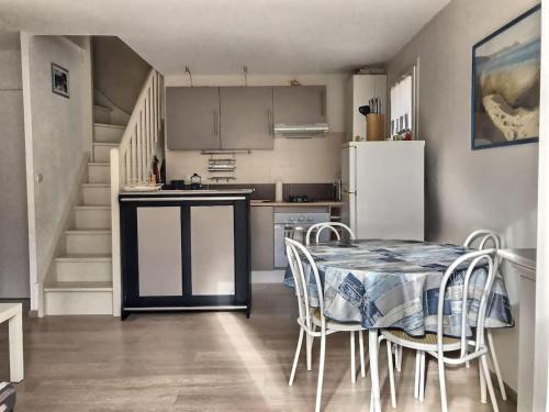 une cuisine avec une table avec des chaises et un réfrigérateur dans l'établissement Confortable pavillon avec jardin à 900m de la plage, à Valras-Plage