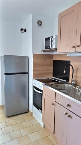 une cuisine avec un réfrigérateur en acier inoxydable et un évier dans l'établissement Agréable appartement avec piscine, à Valras-Plage