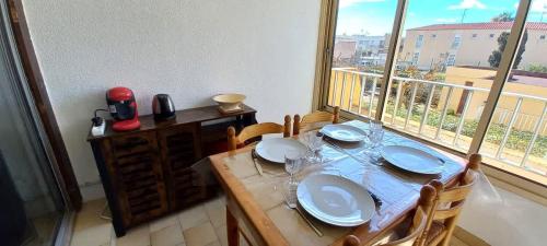 une table de salle à manger avec des assiettes et des verres dessus dans l'établissement Agréable appartement avec piscine, à Valras-Plage