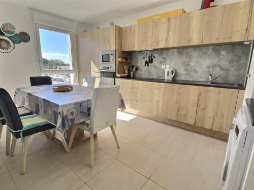 une cuisine avec une table et des chaises et une cuisine avec un comptoir dans l'établissement Appartement avec terrasse à 450m de la plage, à Sérignan