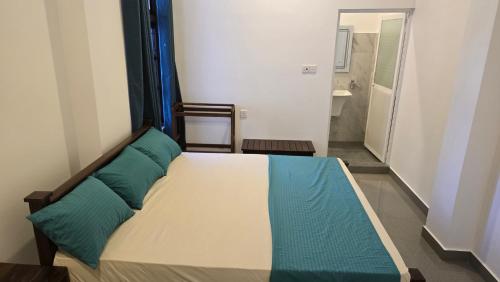 a bedroom with a bed with blue pillows on it at Ramiy Resort Batticaloa in Batticaloa